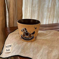 Handmade ceramic mug with playful black and white dinosaur design, resting on linen napkin