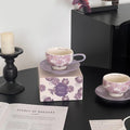 Purple floral ceramic tea cup and saucer set, handmade tableware with 'Morning Light' inscription, styled on black surface